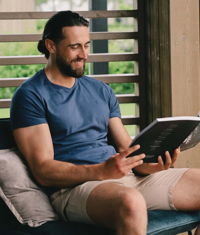 Man in een blauw Undiemeister T-shirt die ontspannen een boek leest